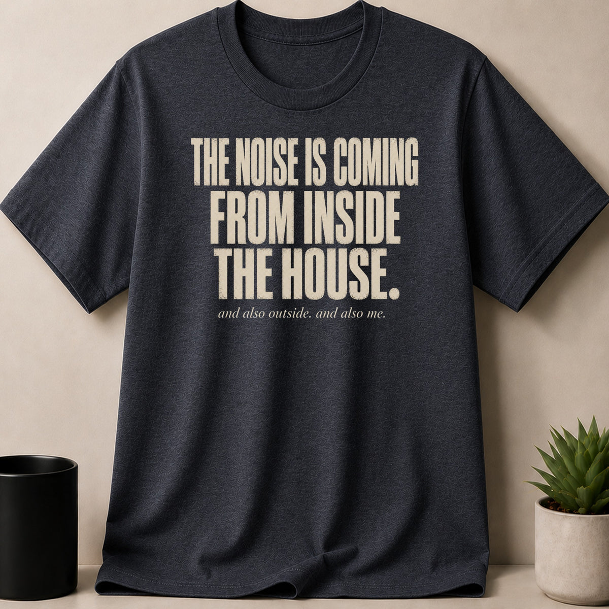 Dark grey t-shirt with text "THE NOISE IS COMING FROM INSIDE THE HOUSE. and also outside. and also me."