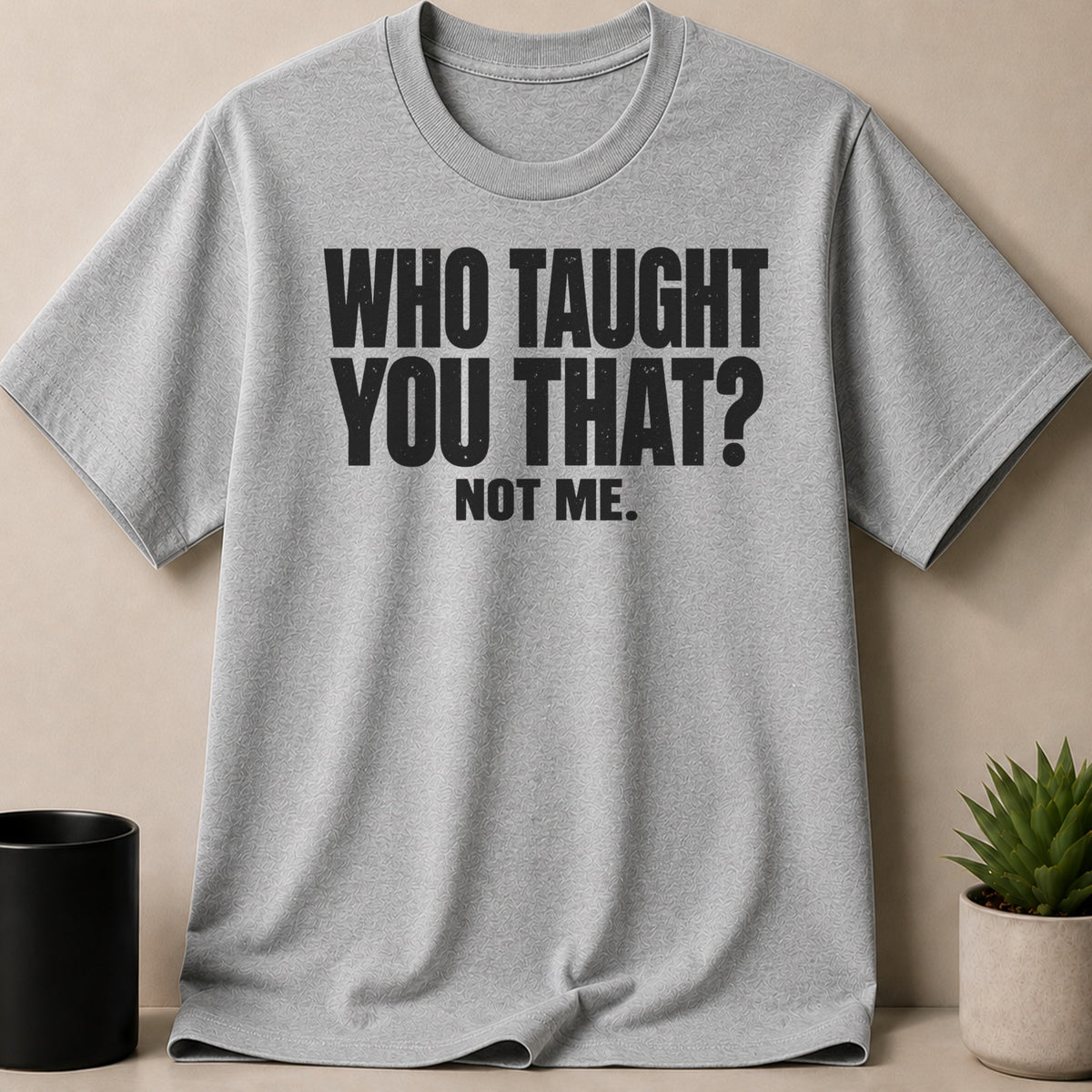 Heather gray crewneck t-shirt featuring the black text WHO TAUGHT YOU THAT? NOT ME.