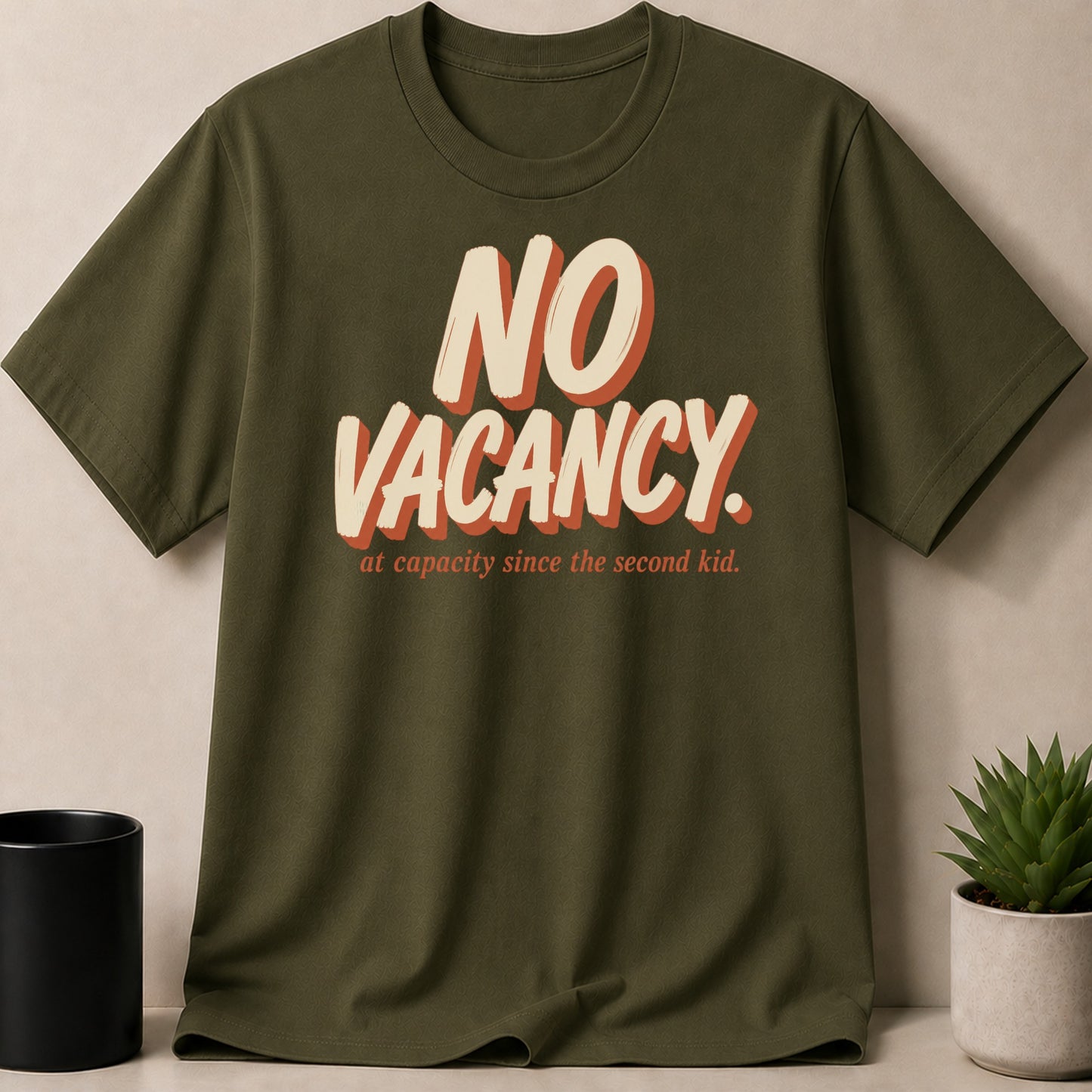 Olive green t-shirt with "NO VACANCY. at capacity since the second kid." text.