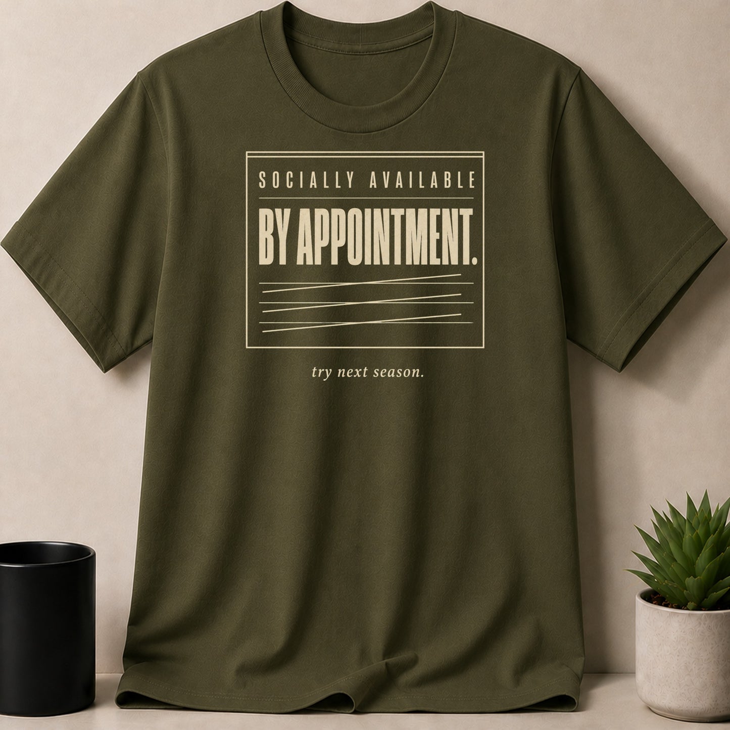 Olive green t-shirt with "Socially Available By Appointment. Try Next Season." text.