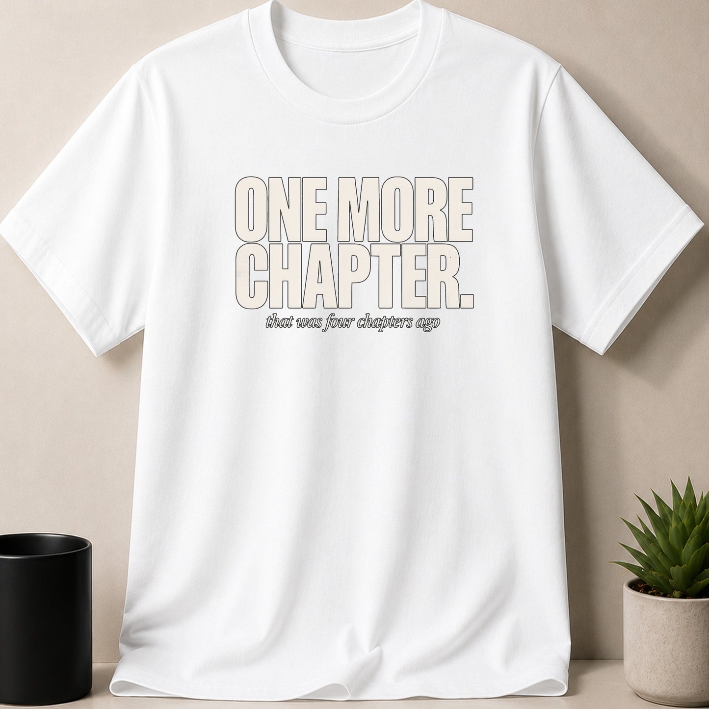 White t-shirt with text "ONE MORE CHAPTER. that was four chapters ago."