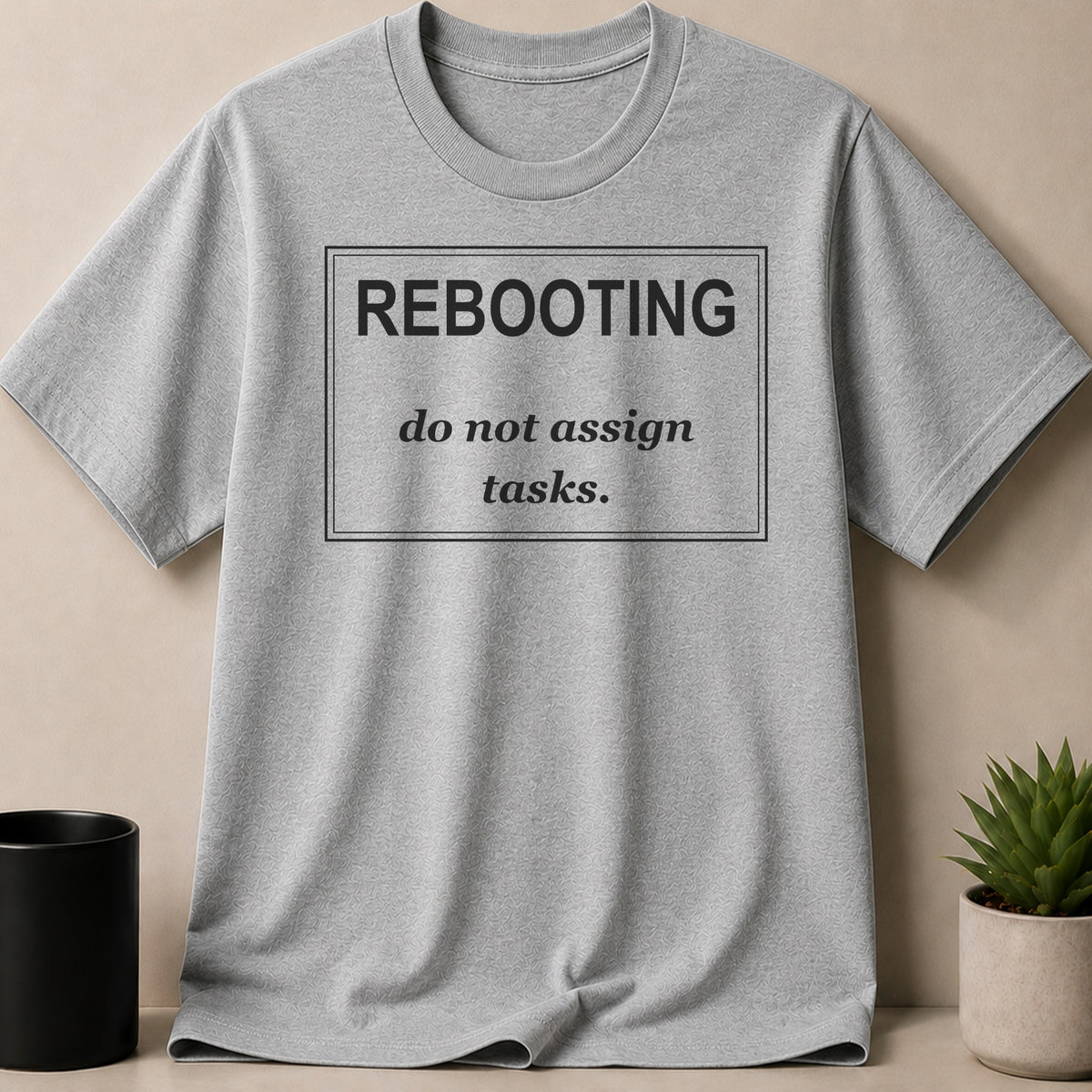 Grey t-shirt with black text "REBOOTING do not assign tasks."
