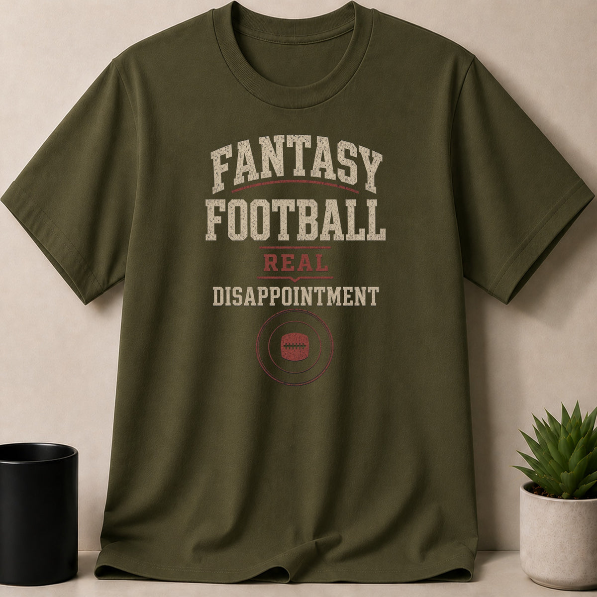 Olive green t-shirt with text "Fantasy Football Real Disappointment" and a football graphic.