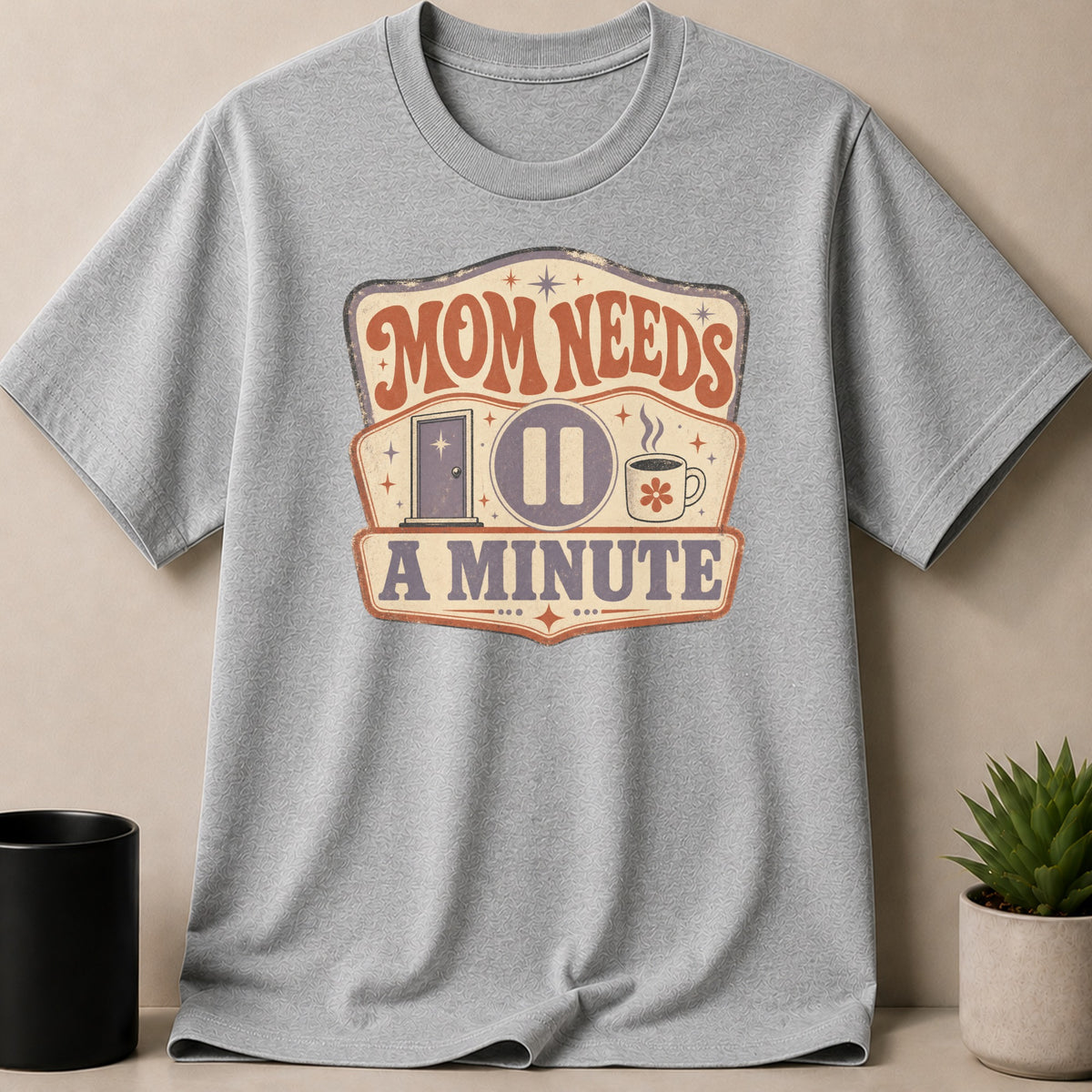 Gray t-shirt with "Mom Needs A Minute" graphic featuring a door, pause button, and coffee cup.