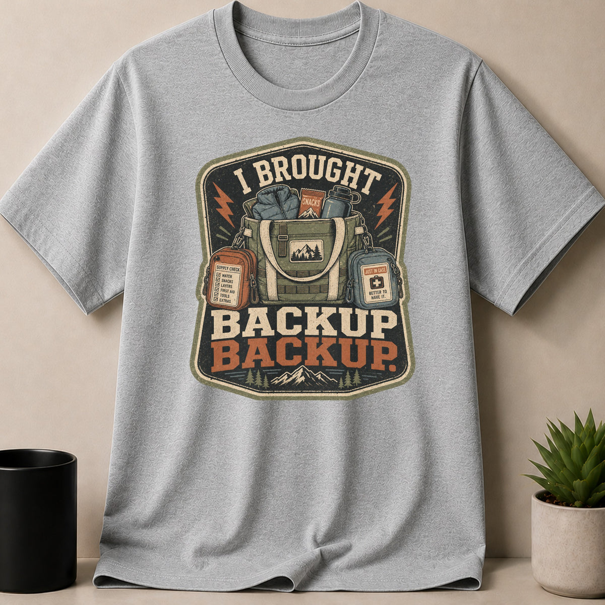Grey t-shirt with "I BROUGHT BACKUP BACKUP" and camping gear graphic.