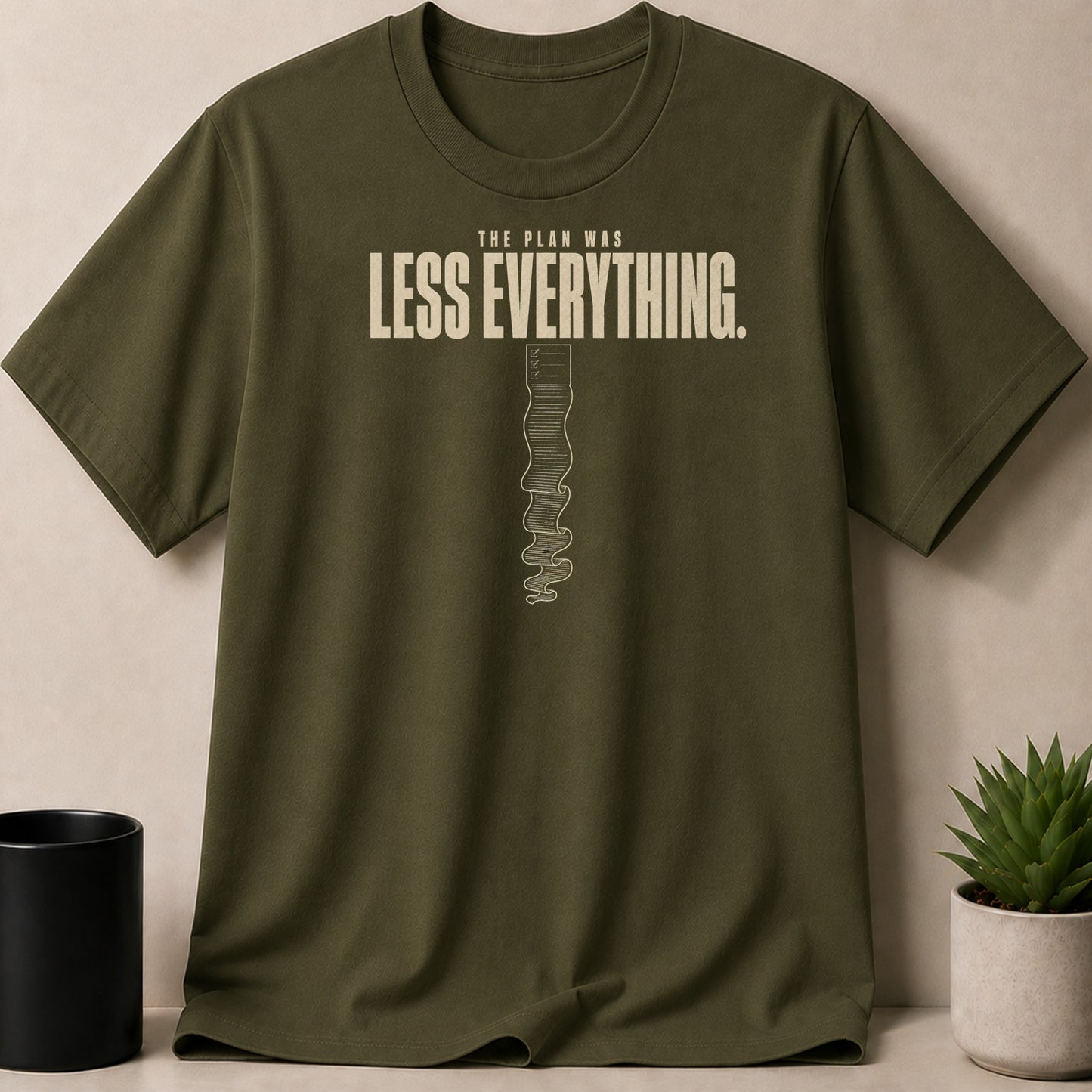 Olive t-shirt with "The plan was LESS EVERYTHING." text and checklist graphic.