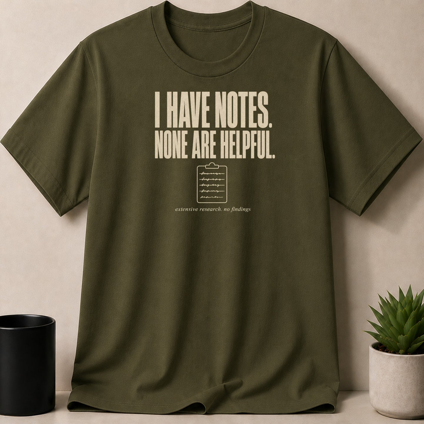 Olive green t-shirt with "I HAVE NOTES. NONE ARE HELPFUL." text and clipboard graphic.