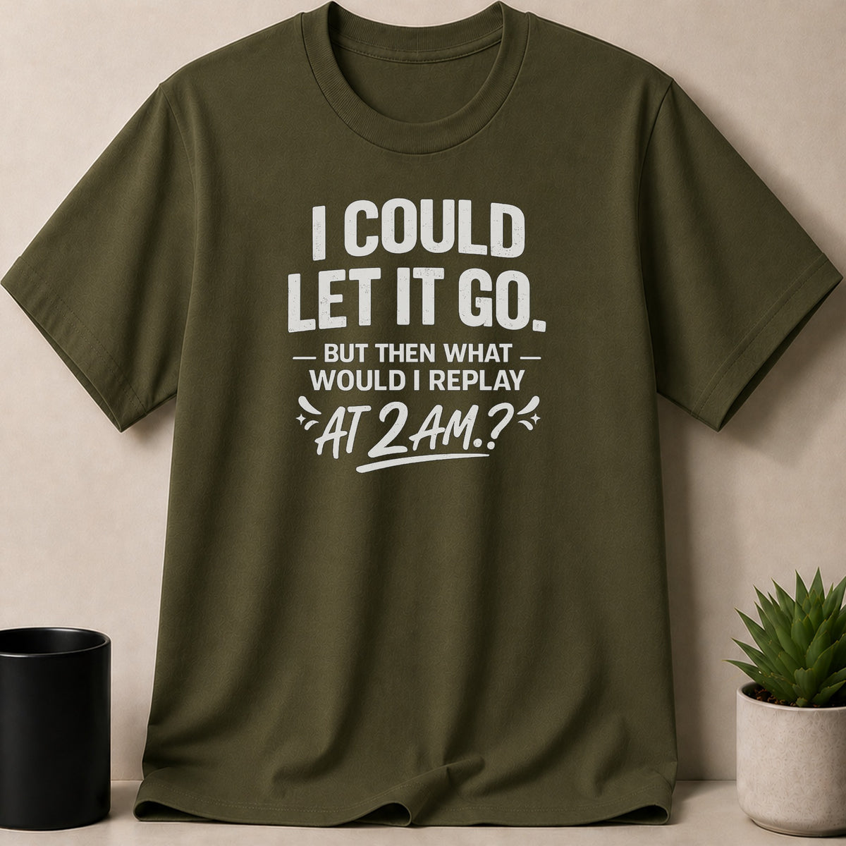 Olive green t-shirt with white text: "I COULD LET IT GO. - BUT THEN WHAT WOULD I REPLAY AT 2 AM.?"