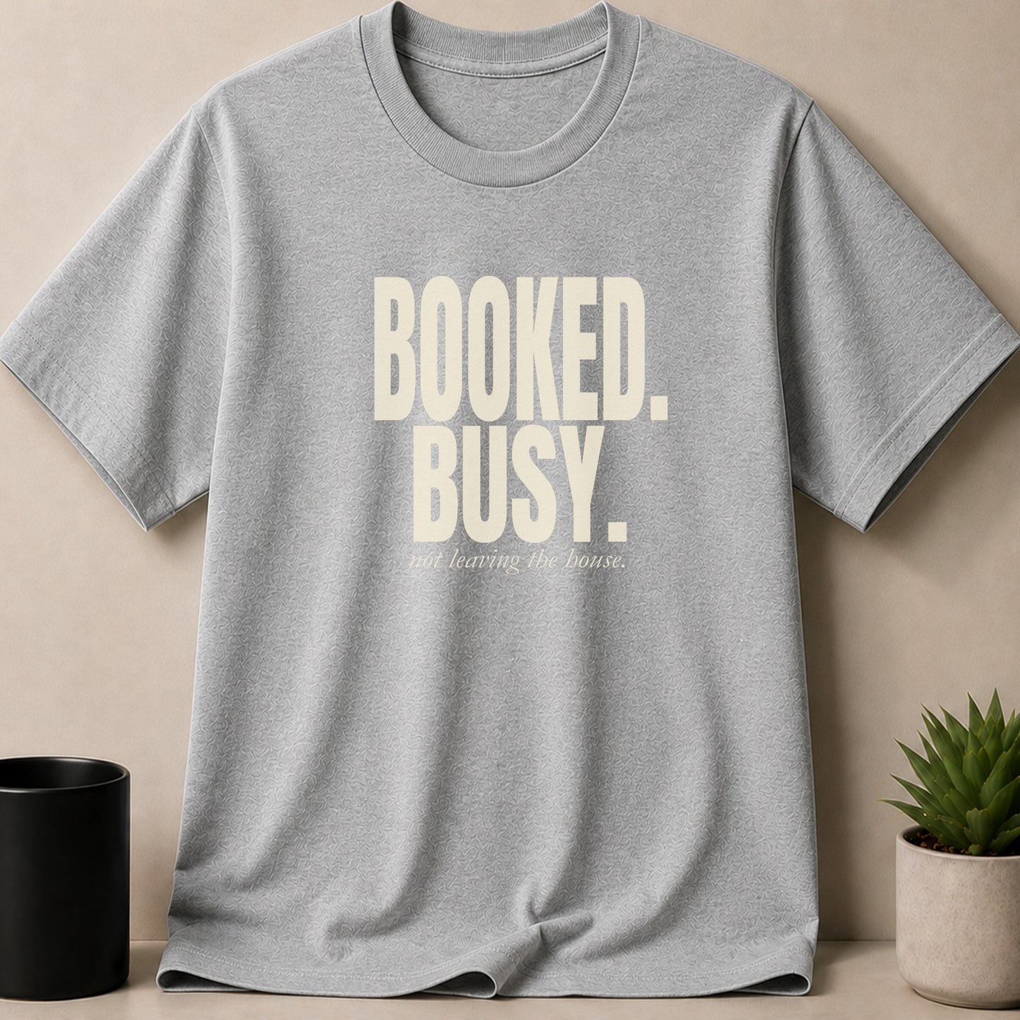 Grey t-shirt with cream text "BOOKED. BUSY. not leaving the house."