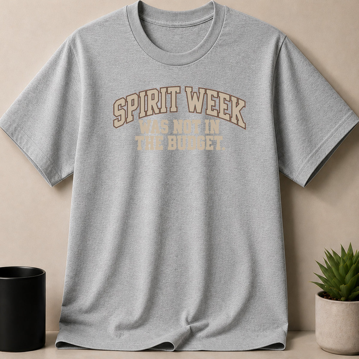 A gray crew neck t-shirt with the brown text Spirit Week Was Not In The Budget centered on the chest.