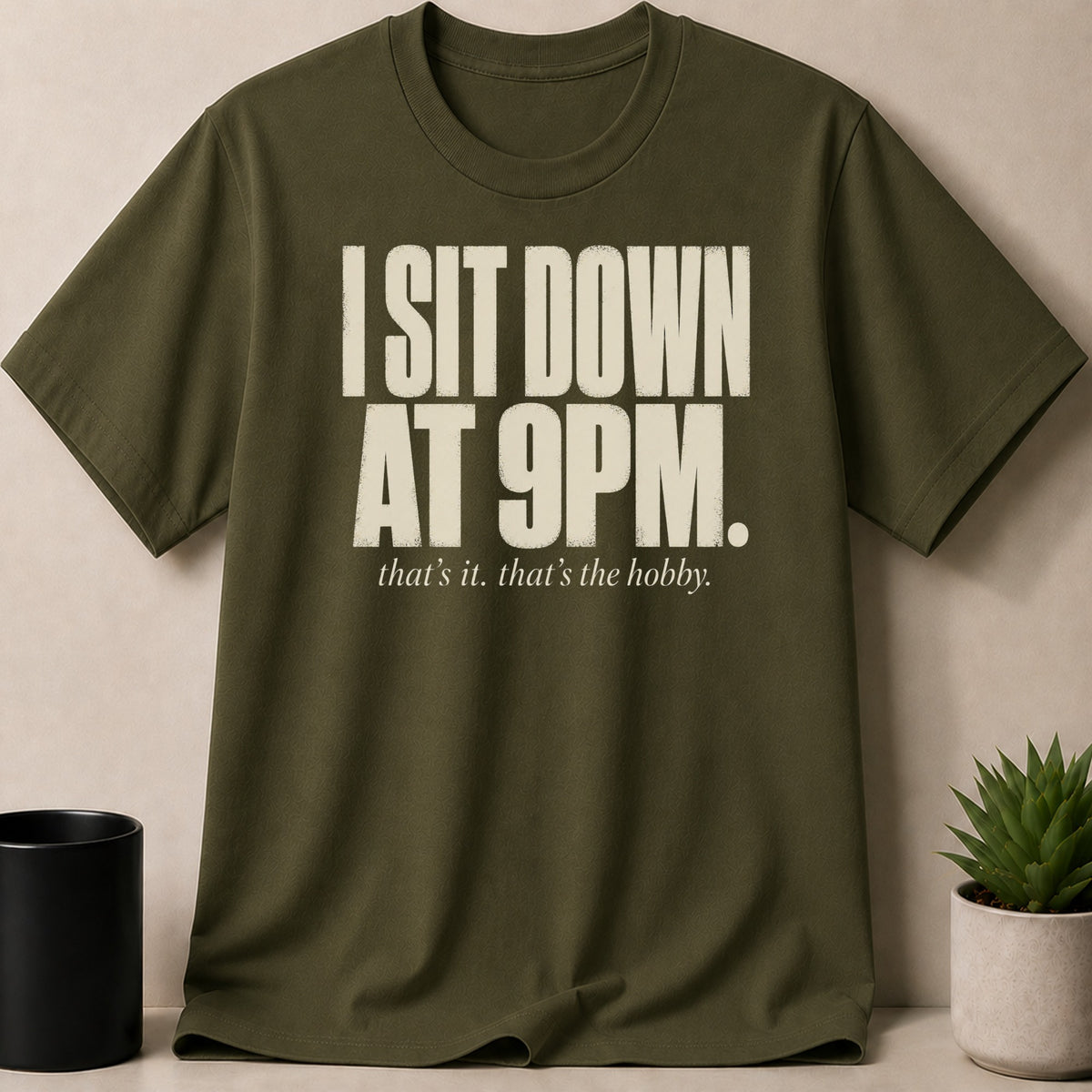 Olive green t-shirt with text "I SIT DOWN AT 9PM. that's it. that's the hobby."