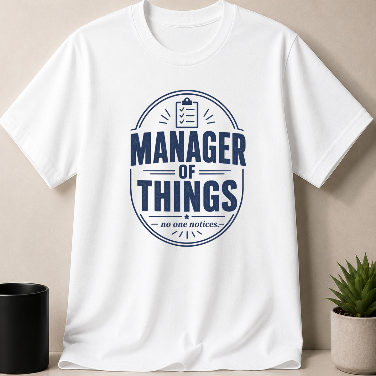 White t-shirt with "MANAGER OF THINGS - no one notices." text and a clipboard graphic.