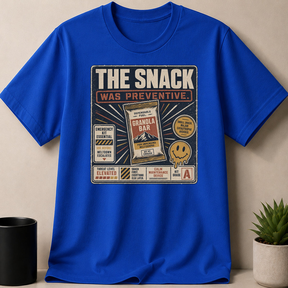 Blue t-shirt with graphic: "THE SNACK WAS PREVENTIVE" and granola bar.
