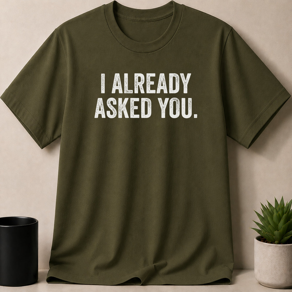 Olive green t-shirt with white text reading "I ALREADY ASKED YOU."