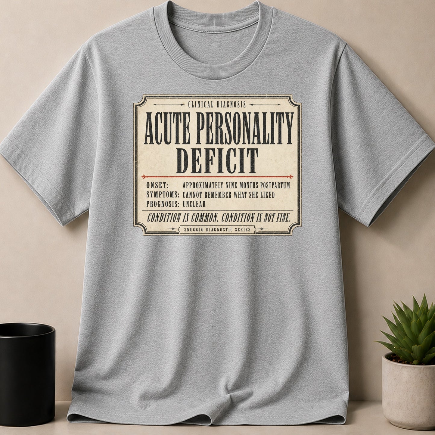 Gray t-shirt with "ACUTE PERSONALITY DEFICIT" diagnostic label design.