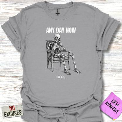Skeleton sitting in a chair with "ANY DAY NOW" and "still here" text.