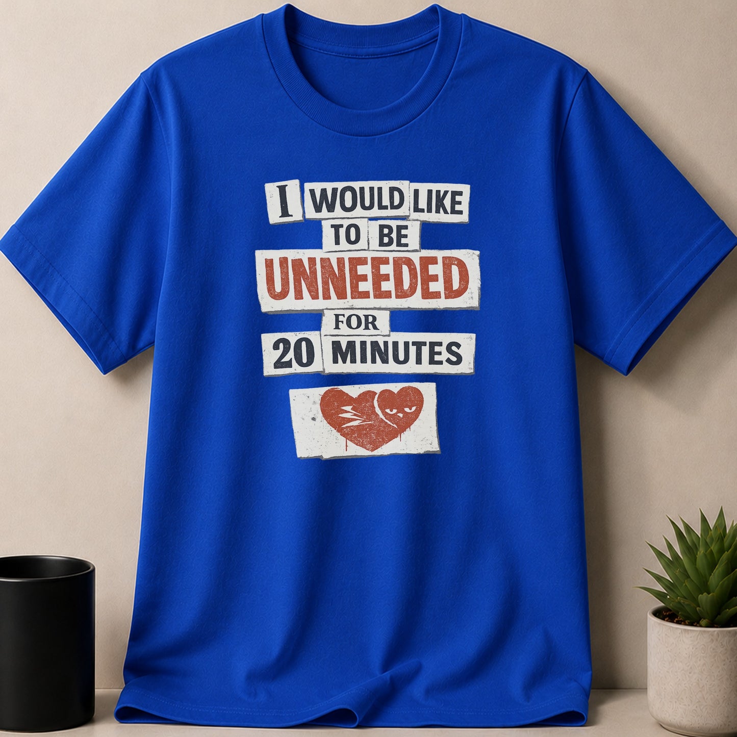 Blue t-shirt with text "I would like to be unneeded for 20 minutes" and a broken heart graphic.