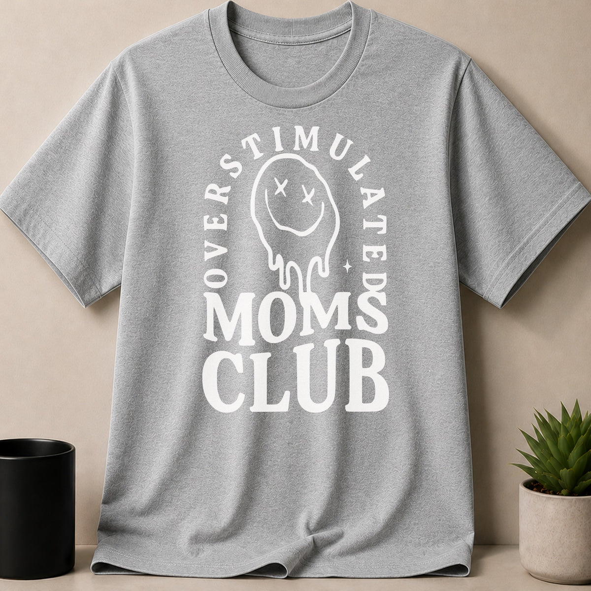Grey t-shirt with "Overstimulated Moms Club" and a melting smiley graphic.