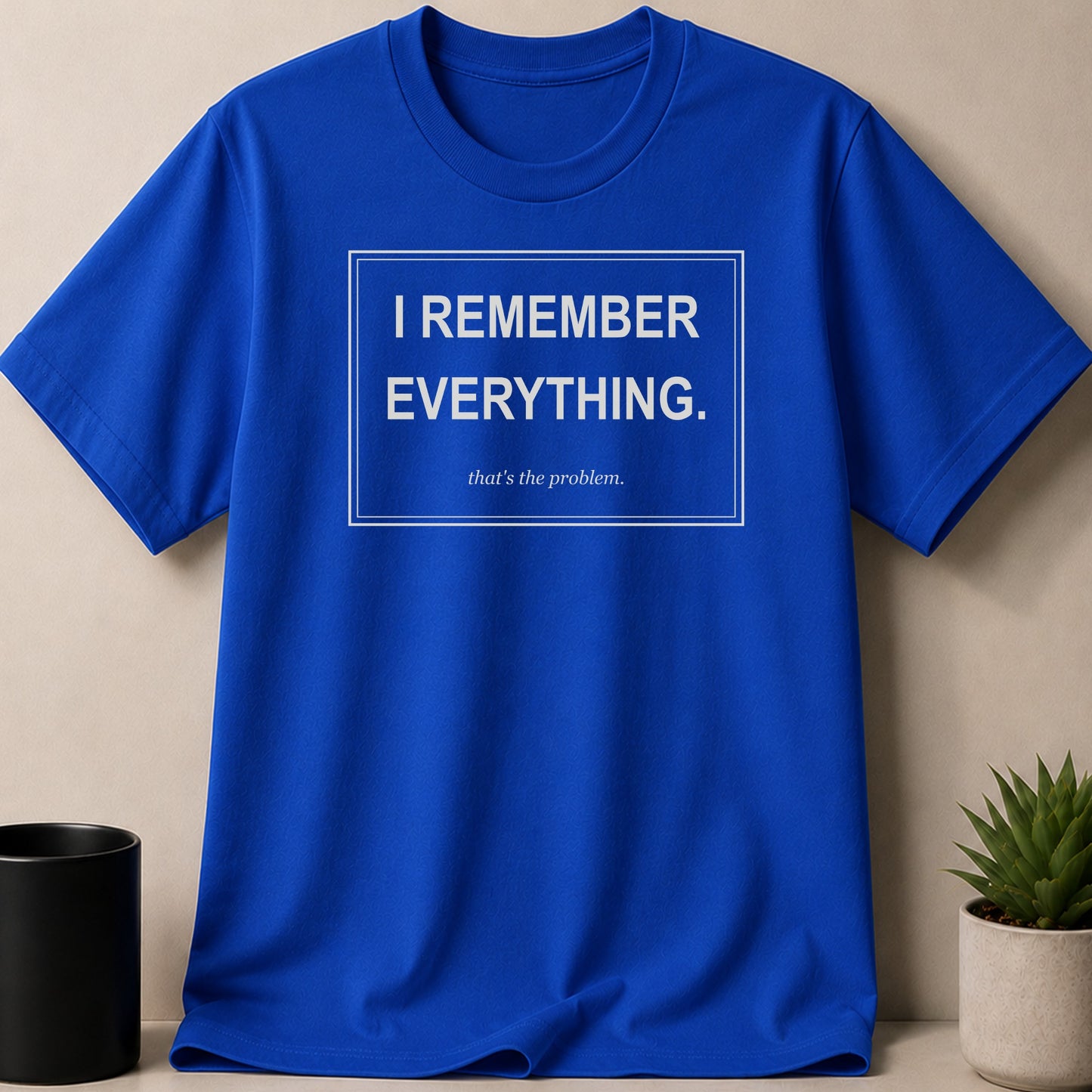 Blue t-shirt with a white rectangle graphic containing text "I REMEMBER EVERYTHING. that's the problem."