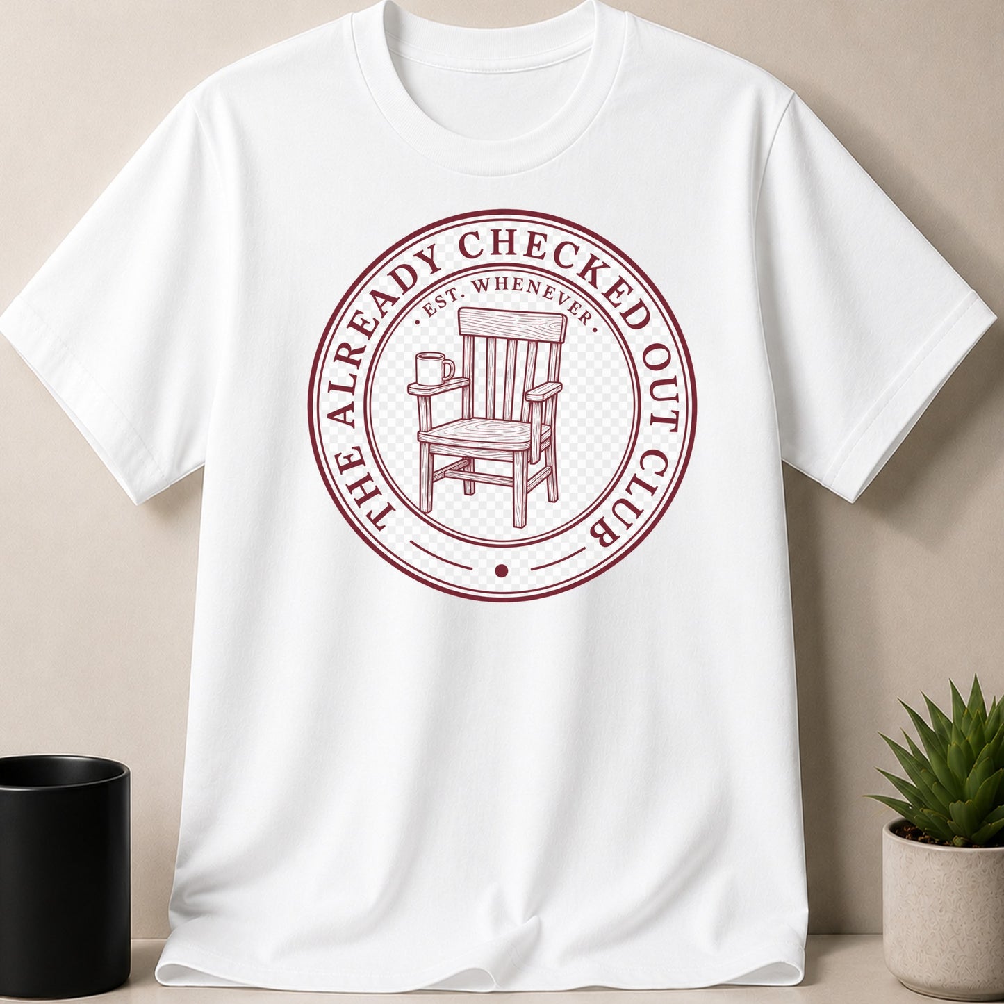 White t-shirt with burgundy emblem featuring a chair and mug, reads "The Already Checked Out Club".