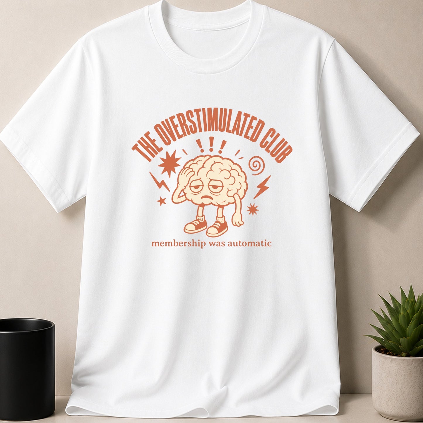 White t-shirt with "The Overstimulated Club" and a tired brain graphic.