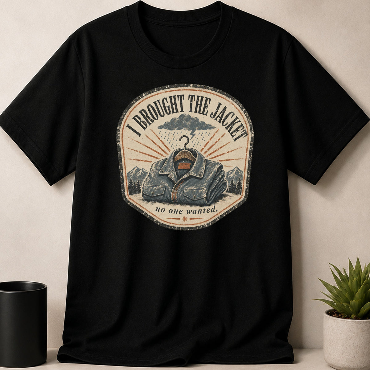 Black t-shirt with a circular graphic of a denim jacket under a stormy sky.