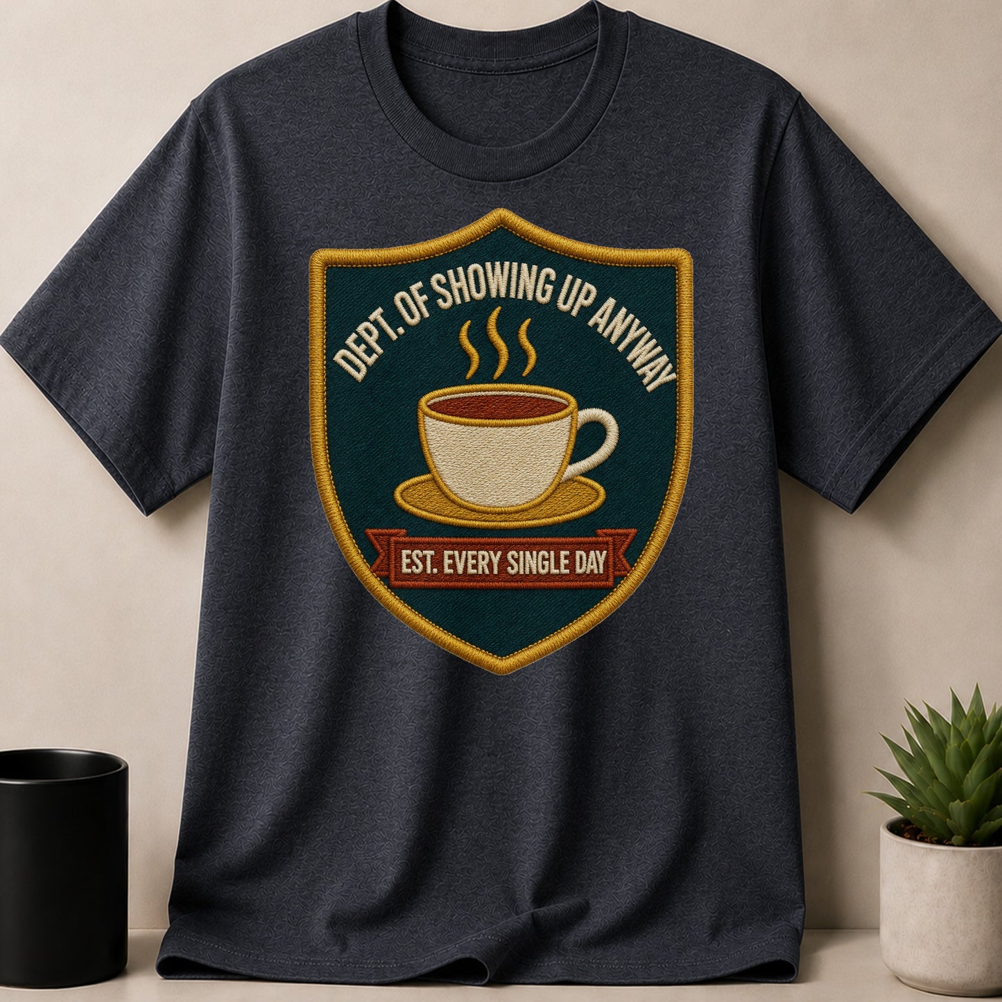 Dark t-shirt with a crest featuring a coffee cup and the text "DEPT. OF SHOWING UP ANYWAY EST. EVERY SINGLE DAY".