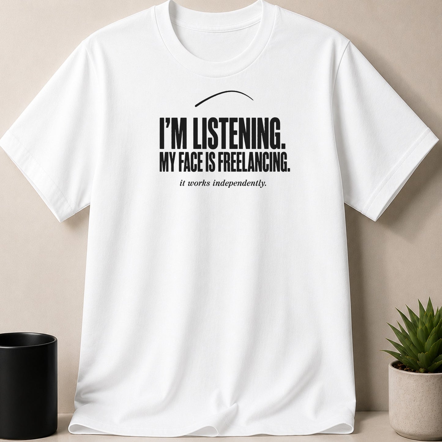 White t-shirt with black text reading "I'M LISTENING. MY FACE IS FREELANCING. it works independently."