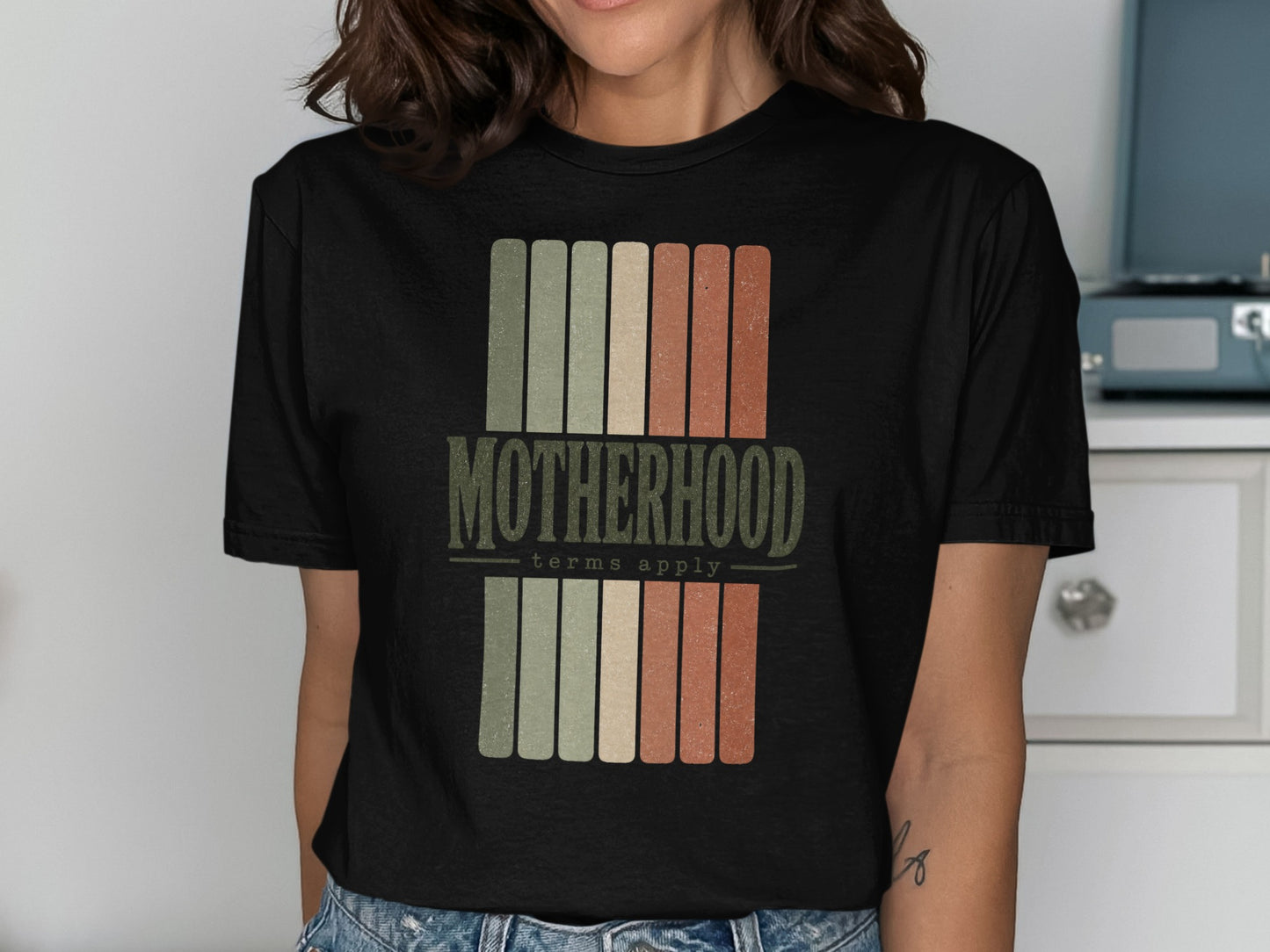 Black t-shirt with "Motherhood terms apply" text and vertical stripes.