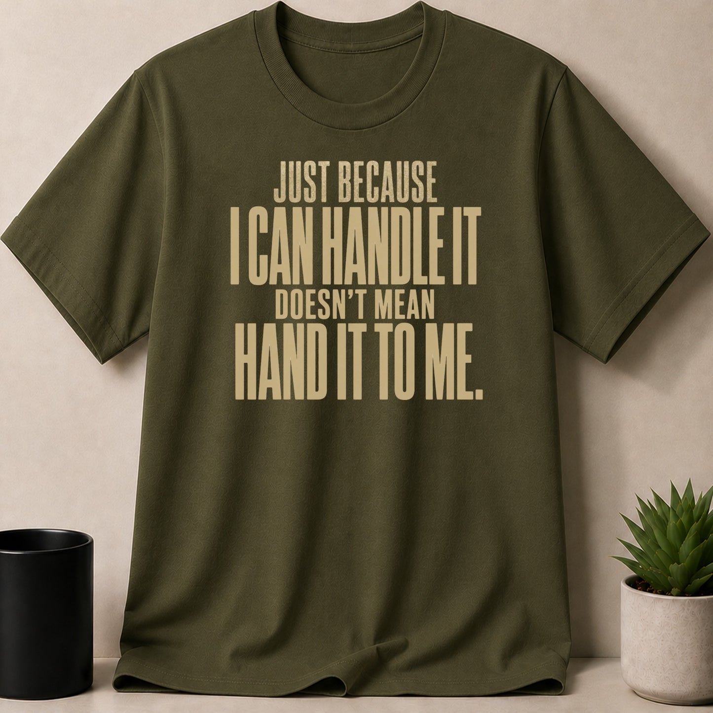 Olive green t-shirt with "Just Because I Can Handle It Doesn't Mean Hand It To Me." text.
