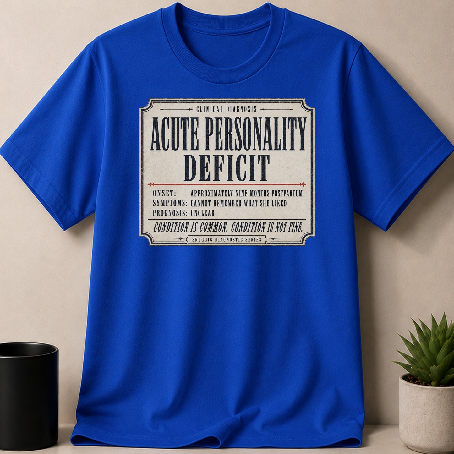 Blue t-shirt with "Acute Personality Deficit" text, a clinical diagnosis.