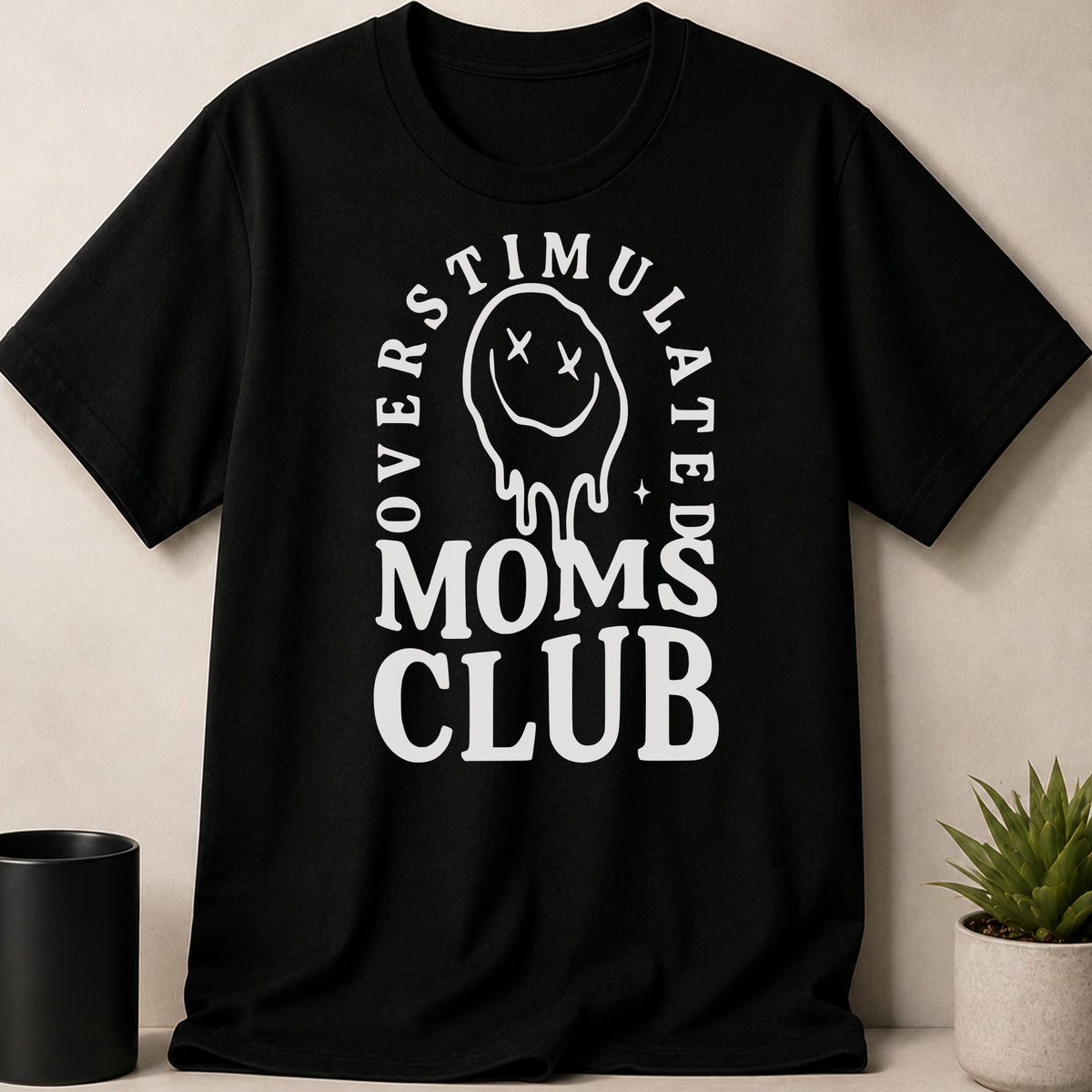 Black t-shirt with white text "Overstimulated Moms Club" and a melting smiley face.
