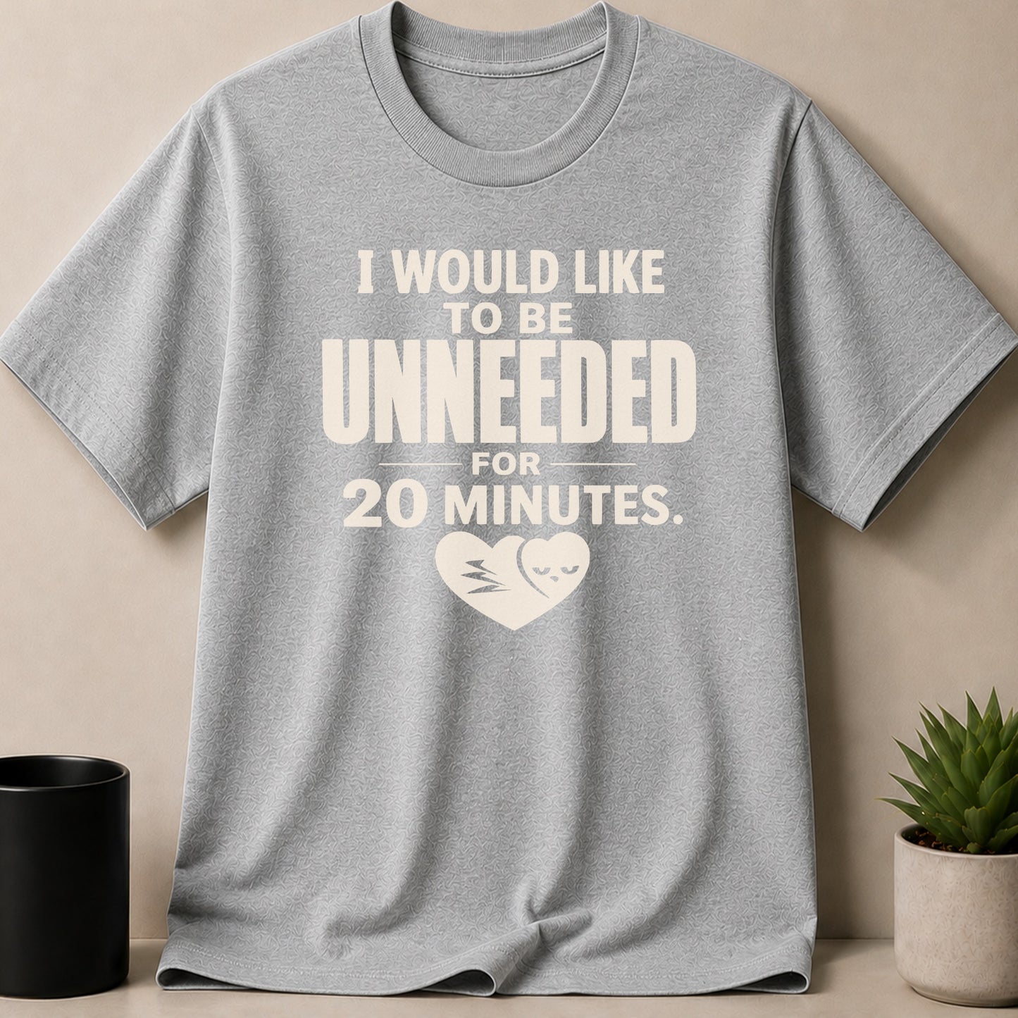 Gray t-shirt with text "I WOULD LIKE TO BE UNNEEDED FOR 20 MINUTES." and heart graphic.