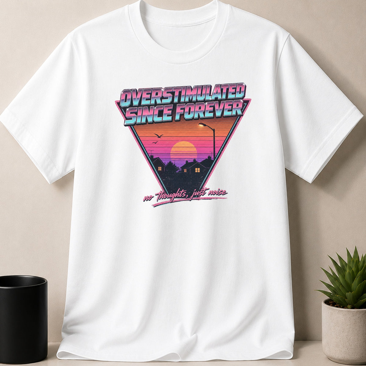 White t-shirt with a retro graphic featuring "OVERSTIMULATED SINCE FOREVER" and "no thoughts, just noise".