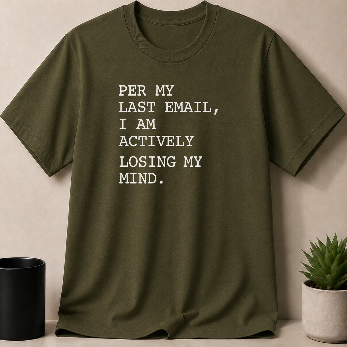 Olive green t-shirt with white text "PER MY LAST EMAIL, I AM ACTIVELY LOSING MY MIND."