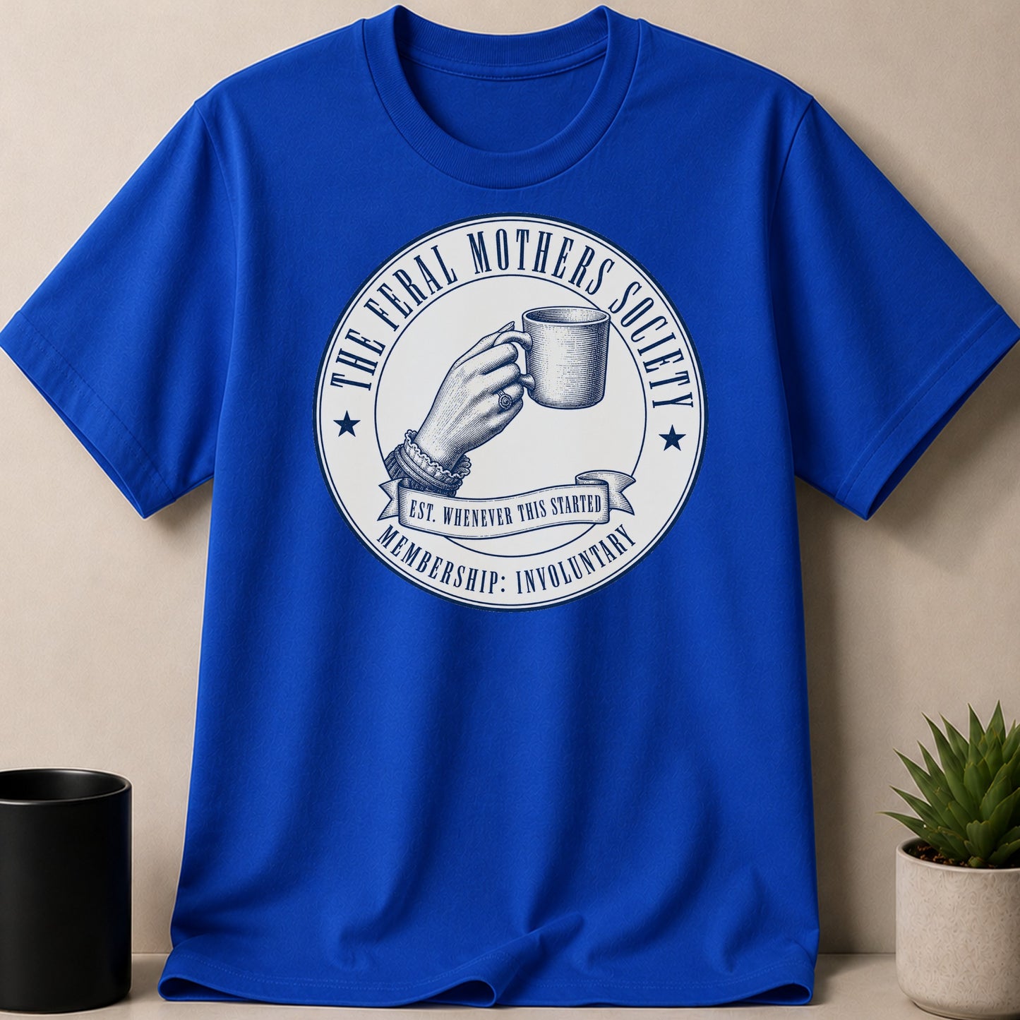 Blue t-shirt with "The Feral Mothers Society" circular logo and text.