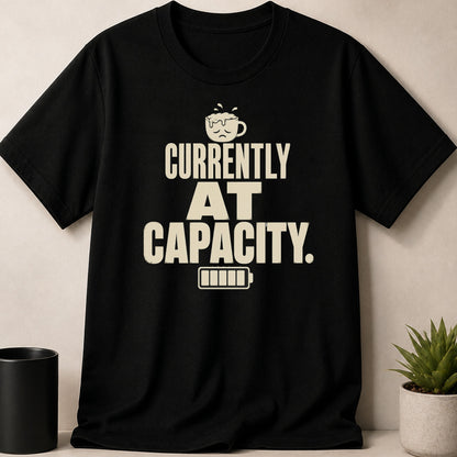 Black t-shirt with "CURRENTLY AT CAPACITY." text and a sad coffee cup icon.