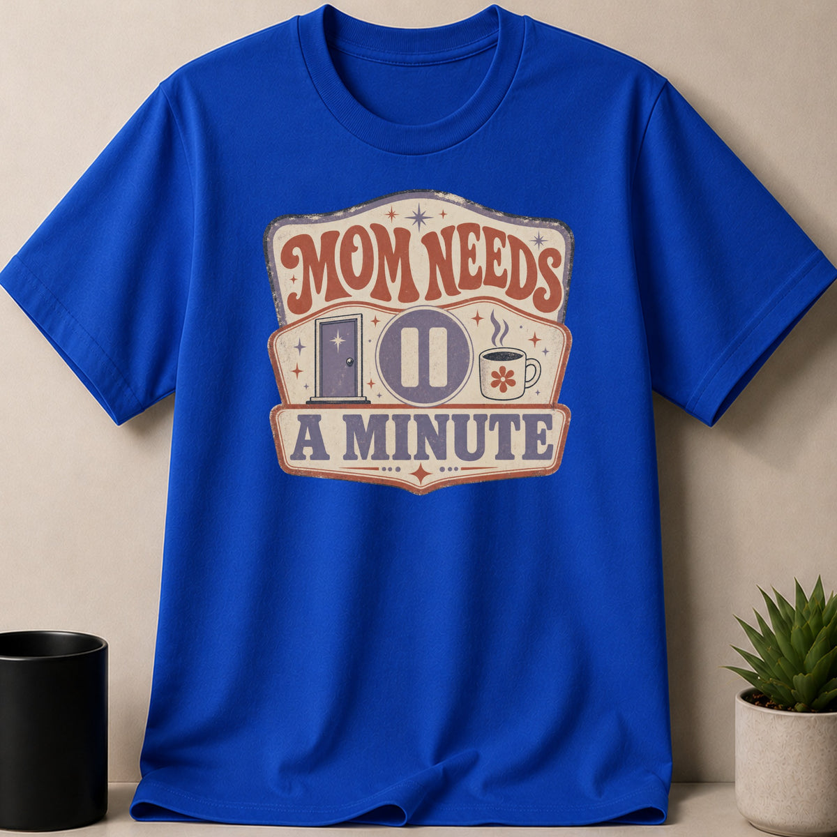 Blue t-shirt with "Mom Needs A Minute" graphic featuring a door, pause button, and coffee cup.