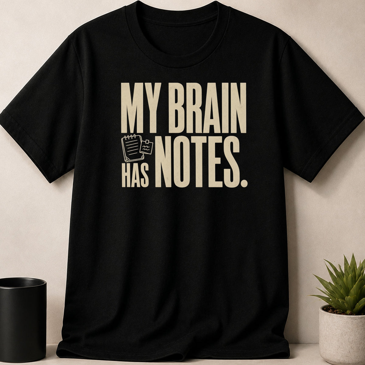 Black t-shirt with text "MY BRAIN HAS NOTES." and a notebook icon.