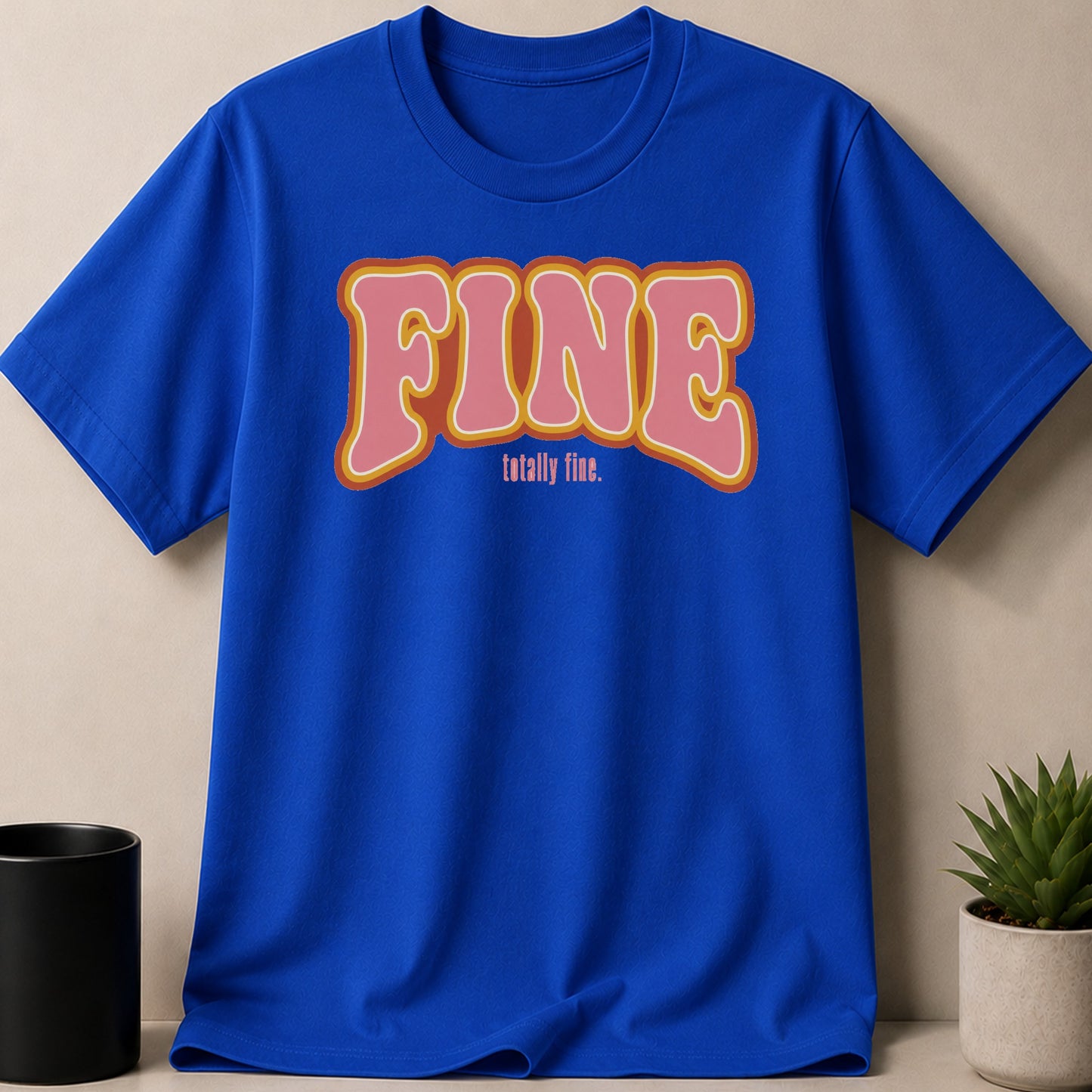 Blue t-shirt with pink and orange "FINE totally fine" graphic text.