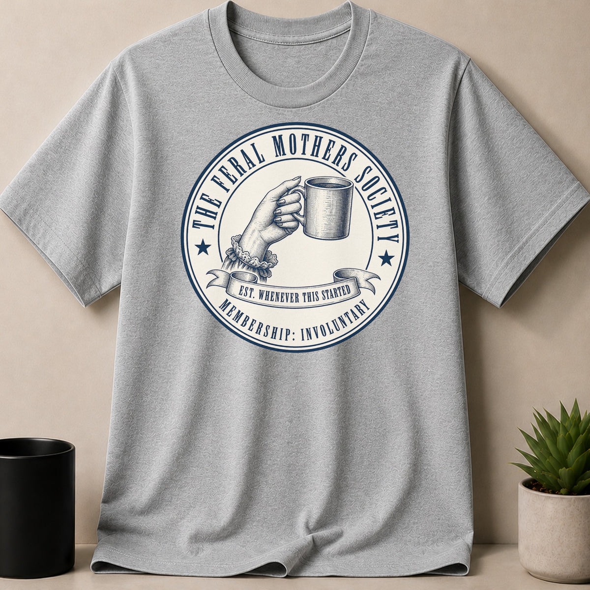 Grey t-shirt with "The Feral Mothers Society" graphic on a mug.