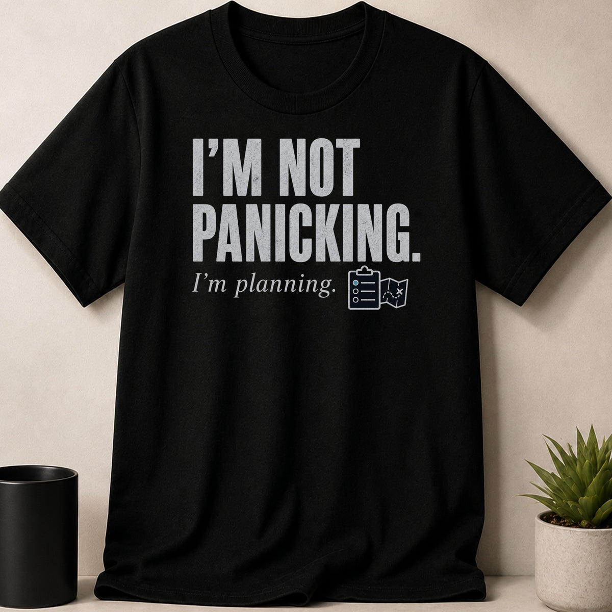 Black t-shirt with distressed text "I'M NOT PANICKING. I'm planning." and planning icons.