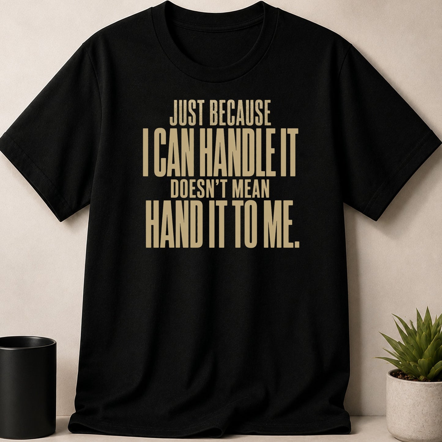 Black t-shirt with gold text reading "JUST BECAUSE I CAN HANDLE IT DOESN'T MEAN HAND IT TO ME."