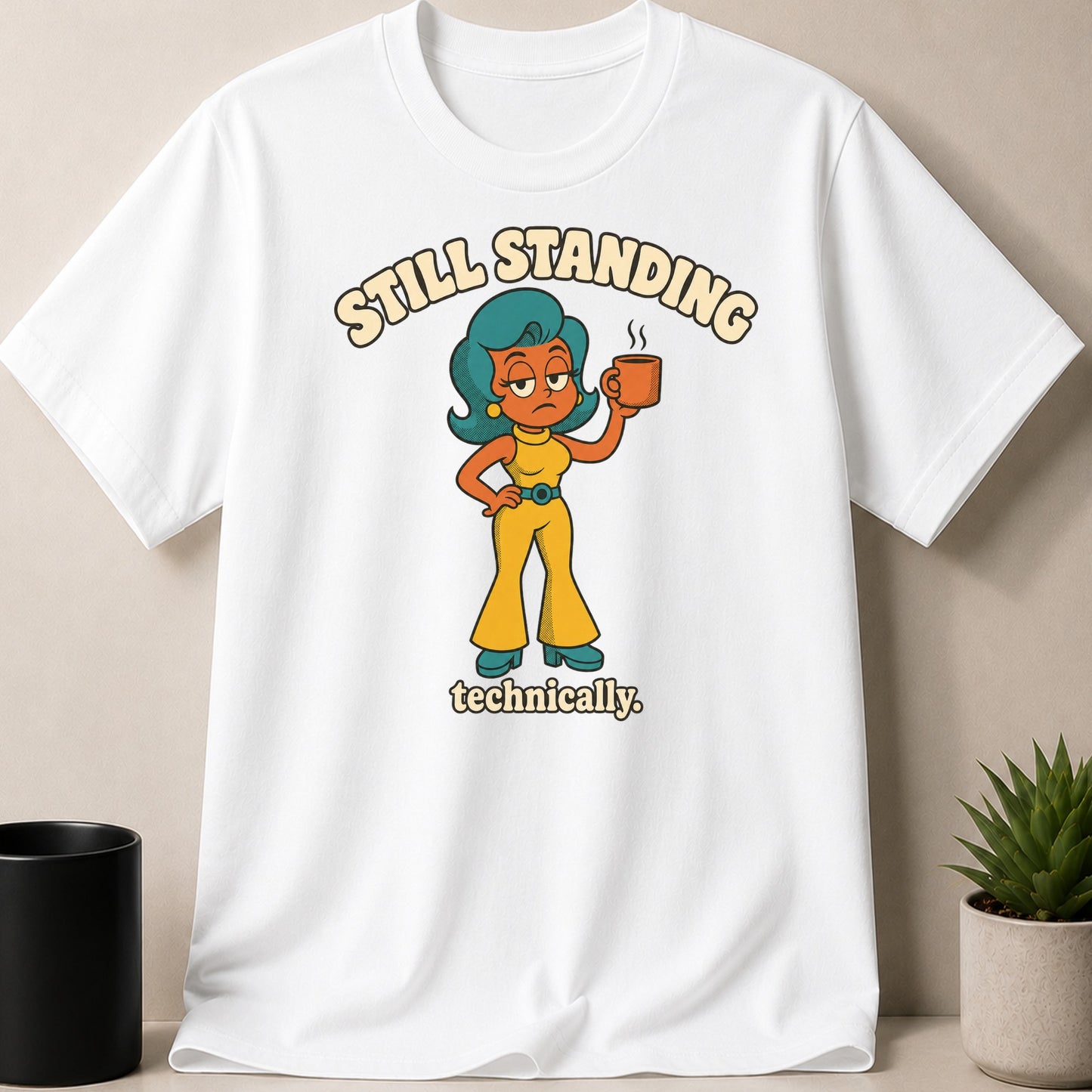 White t-shirt with graphic "Still Standing technically" and cartoon woman holding coffee.