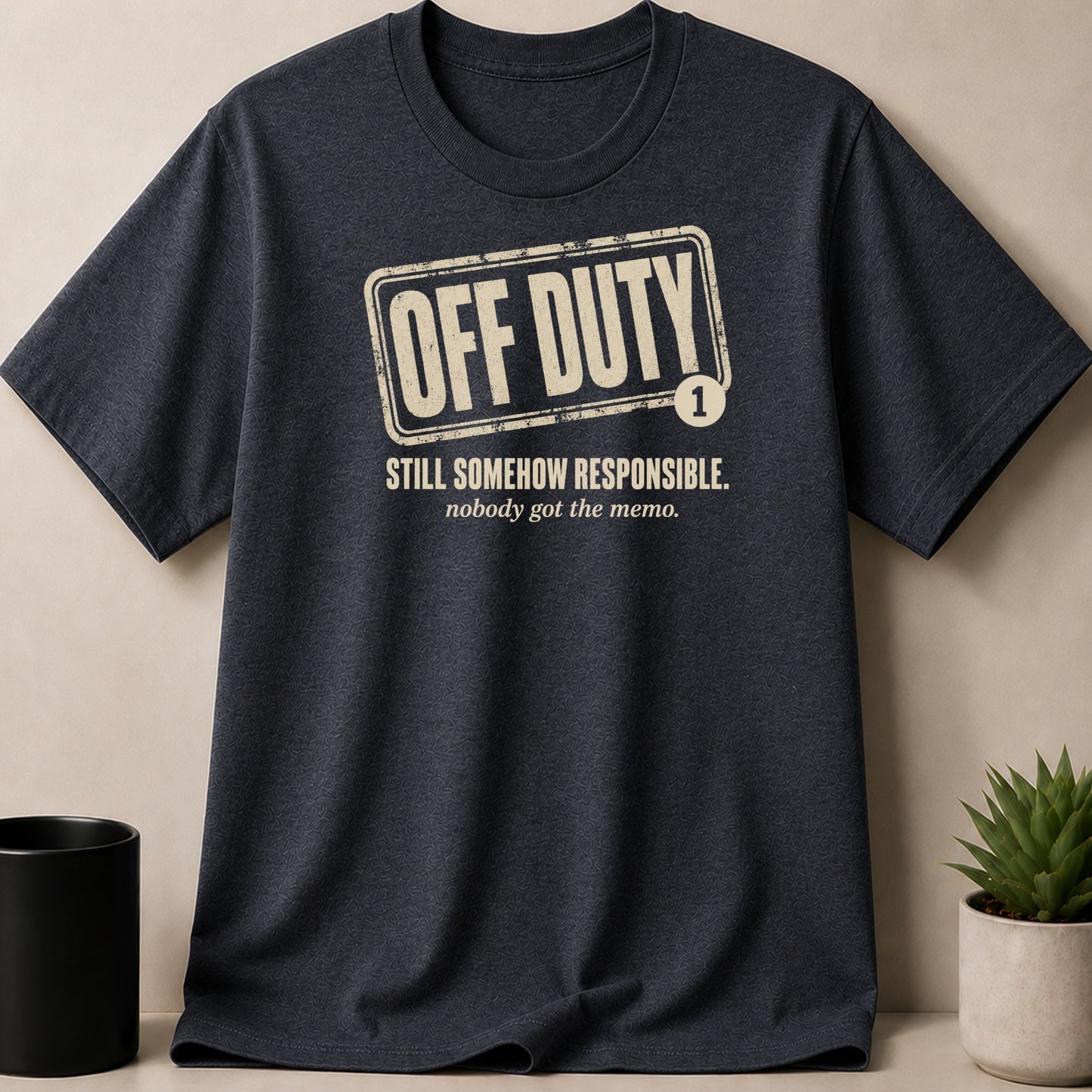Dark grey t-shirt with distressed "OFF DUTY" text and "STILL SOMEHOW RESPONSIBLE."