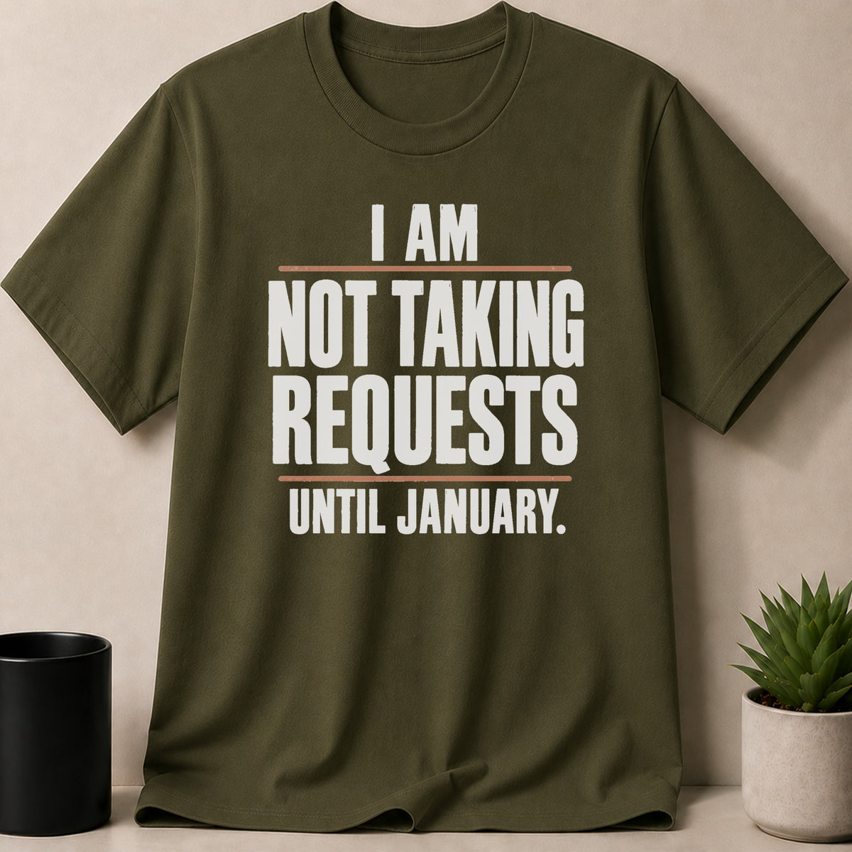 An olive green t-shirt with white text that reads I AM NOT TAKING REQUESTS UNTIL JANUARY.