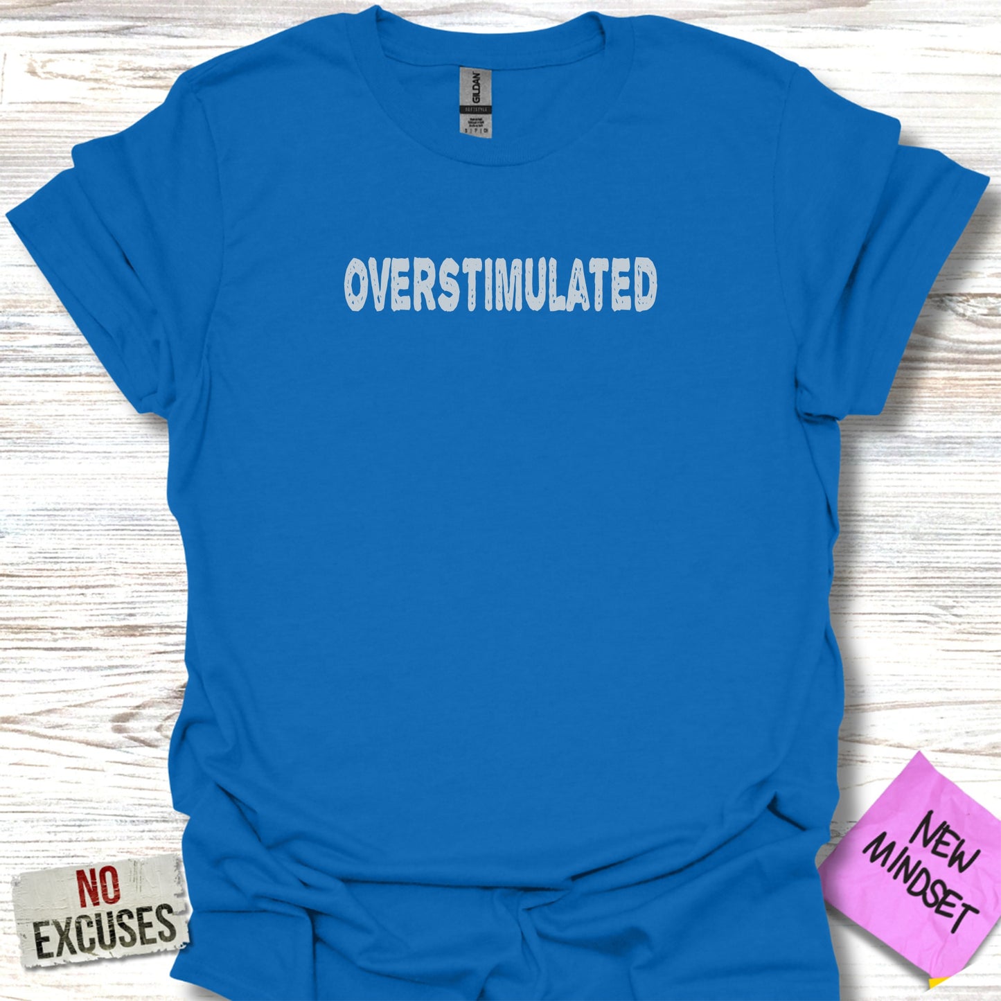 Blue t-shirt with "OVERSTIMULATED" text and "NO EXCUSES" tag.