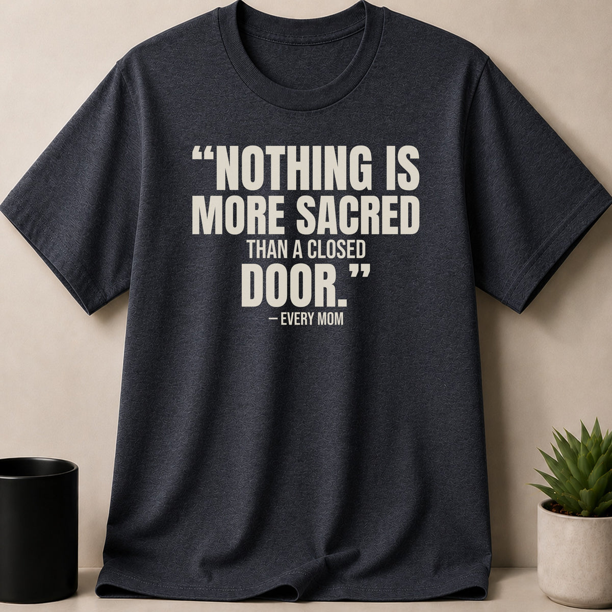 Dark grey crewneck t-shirt featuring white text that reads, Nothing is more sacred than a closed door. Every Mom.