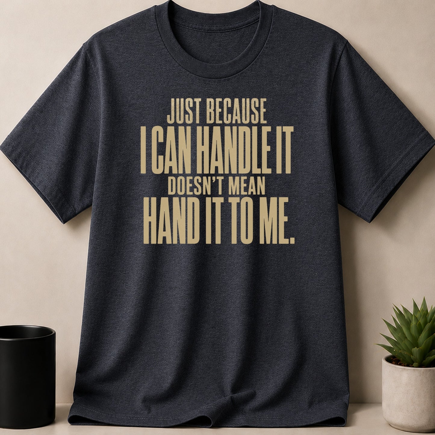 Dark grey t-shirt with gold text "Just because I can handle it doesn't mean hand it to me."