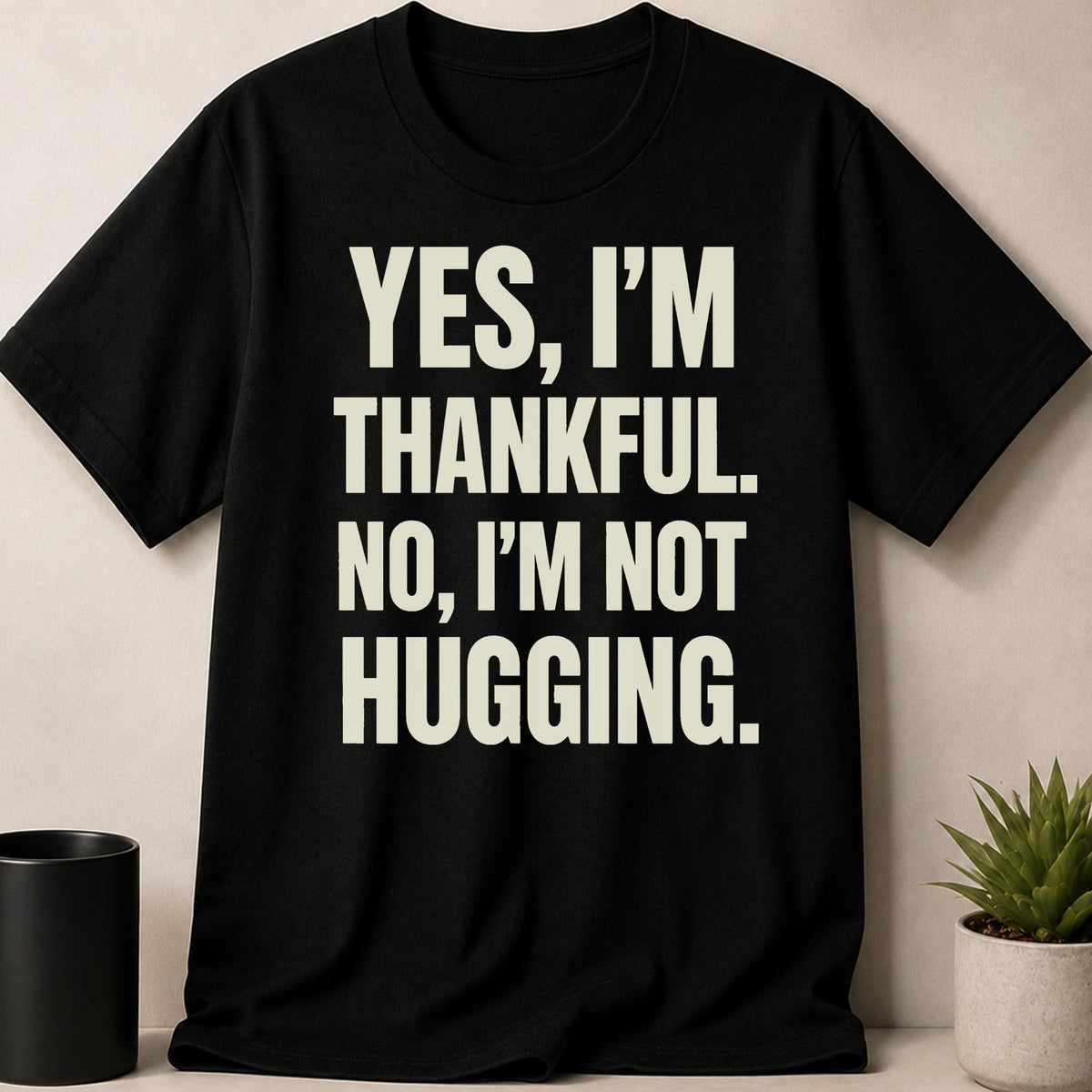 Black t-shirt with "YES, I'M THANKFUL. NO, I'M NOT HUGGING." text in beige.